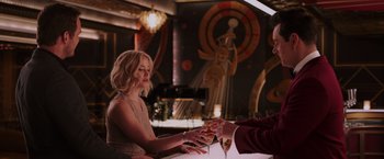 Movie still from “Passengers” (2016), directed by Morten Tyldum – A woman is holding a glass of wine in her hand; Medium shot, Over the shoulder angle