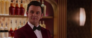 Movie still from “Passengers” (2016), directed by Morten Tyldum – A man in a red jacket and a bow tie; Close Up shot, Over the shoulder angle