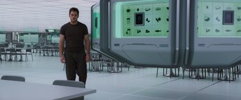 Movie still from “Passengers” (2016), directed by Morten Tyldum – A man standing next to a table in front of a computer screen; Wide shot, Over the shoulder angle
