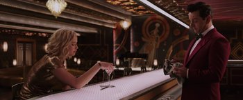 Movie still from “Passengers” (2016), directed by Morten Tyldum – A woman sitting at a bar holding a wine glass; Medium shot, Over the shoulder angle