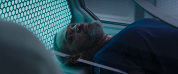 Movie still from “Passengers” (2016), directed by Morten Tyldum – A man laying on the ground in a room; Close Up shot, Overhead angle