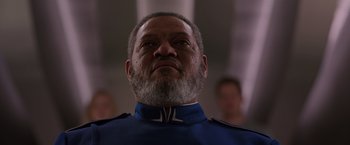 Movie still from “Passengers” (2016), directed by Morten Tyldum – An older man with a beard wearing a blue uniform; Close Up shot, Low angle