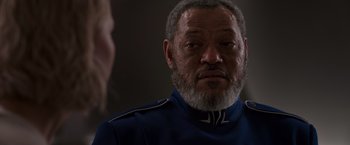 Movie still from “Passengers” (2016), directed by Morten Tyldum – An older man with a beard wearing a blue uniform; Close Up shot, Over the shoulder angle