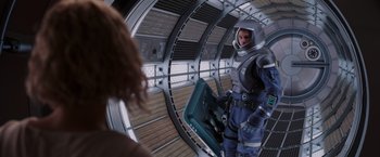Movie still from “Passengers” (2016), directed by Morten Tyldum – A person in a spacesuit holding a suitcase; Medium shot, Over the shoulder angle