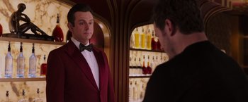 Movie still from “Passengers” (2016), directed by Morten Tyldum – A man in a red suit is looking at another man in a red suit; Medium shot, Over the shoulder angle