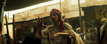 Movie still from “Pathaan” (2023), directed by Siddharth Anand – A man wearing a red turban is holding his hands up; Medium shot, Over the shoulder angle