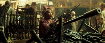 Movie still from “Pathaan” (2023), directed by Siddharth Anand – A woman is holding a bunch of guns in her hands; Medium shot, Over the shoulder angle