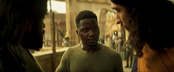 Movie still from “Pathaan” (2023), directed by Siddharth Anand – A man standing next to another man in front of a building; Close Up shot, Over the shoulder angle