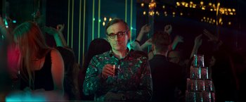 Movie still from “Pathaan” (2023), directed by Siddharth Anand – A man in a green shirt holding a glass of wine; Medium shot, Low angle