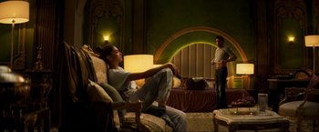 Movie still from “Pathaan” (2023), directed by Siddharth Anand – A man and a woman sitting on a couch in a living room; Wide shot, Low angle
