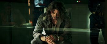 Movie still from “Pathaan” (2023), directed by Siddharth Anand – A man with long hair is looking at his wrist watch; Medium shot, Over the shoulder angle