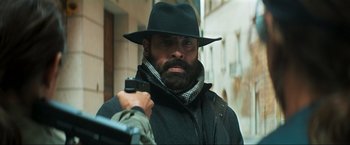 Movie still from “Pathaan” (2023), directed by Siddharth Anand – A man with a beard and a black hat holding a gun; Medium shot, Over the shoulder angle