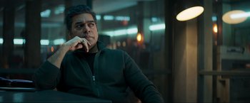 Movie still from “Pathaan” (2023), directed by Siddharth Anand – A man sitting in a chair with his hand under his chin; Medium shot, Low angle