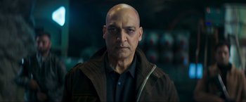 Movie still from “Pathaan” (2023), directed by Siddharth Anand – A man with bald head wearing a brown jacket; Close Up shot, Low angle