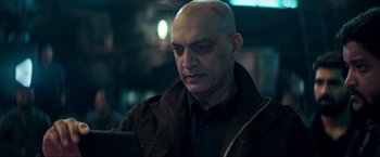 Movie still from “Pathaan” (2023), directed by Siddharth Anand – A bald man looking at his cell phone; Close Up shot, Low angle