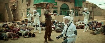 Movie still from “Pathaan” (2023), directed by Siddharth Anand – A group of men in white suits are standing in the dirt; Wide shot, Over the shoulder angle