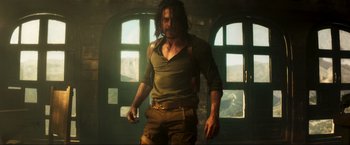 Movie still from “Pathaan” (2023), directed by Siddharth Anand – A man with long dark hair is standing in front of a window; Medium shot, Low angle