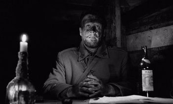 Movie still from “Paths of Glory” (1957), directed by Stanley Kubrick – A man in a military uniform sitting at a table with his hands clasped together; Medium shot, Low angle