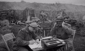 Movie still from “Paths of Glory” (1957), directed by Stanley Kubrick – Two men sitting at a table in front of a field; Medium shot, High angle