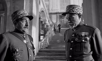 Movie still from “Paths of Glory” (1957), directed by Stanley Kubrick – A couple of men standing next to each other on some stairs; Medium shot, Low angle