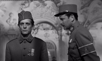 Movie still from “Paths of Glory” (1957), directed by Stanley Kubrick – Two men in military uniforms stand next to each other in front of an ornate wall; Medium shot, Low angle