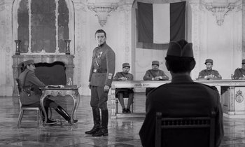 Movie still from “Paths of Glory” (1957), directed by Stanley Kubrick – A man in a uniform stands in front of a group of people; Wide shot, Low angle