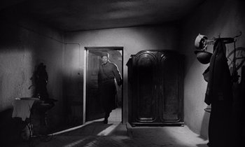 Movie still from “Paths of Glory” (1957), directed by Stanley Kubrick – A black and white photo of a man walking through an open door; Wide shot, Low angle