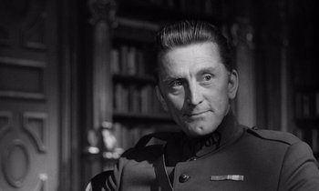 Movie still from “Paths of Glory” (1957), directed by Stanley Kubrick – A man in a military uniform in front of bookshelves; Close Up shot, Low angle