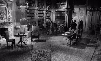 Movie still from “Paths of Glory” (1957), directed by Stanley Kubrick – A room filled with lots of bookshelves and chairs; Wide shot, High angle