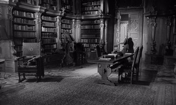 Movie still from “Paths of Glory” (1957), directed by Stanley Kubrick – A room filled with lots of bookshelves filled with lots of books; Wide shot, High angle