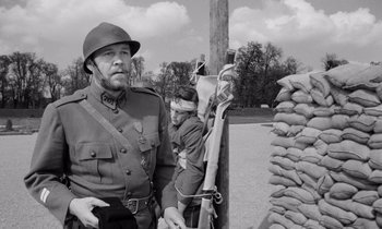 Movie still from “Paths of Glory” (1957), directed by Stanley Kubrick – An old photo of a man in a military uniform; Medium shot, Over the shoulder angle