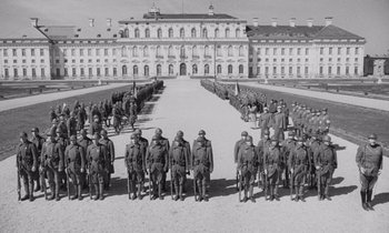 Movie still from “Paths of Glory” (1957), directed by Stanley Kubrick – A black - and - white photo of a group of men standing in front of a building; Wide shot, High angle
