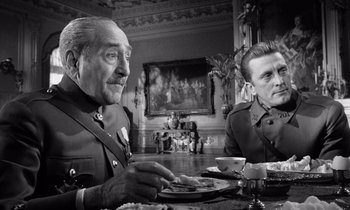 Movie still from “Paths of Glory” (1957), directed by Stanley Kubrick – Two men sitting at a dinner table in a dining room; Medium shot, Over the shoulder angle