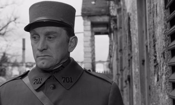 Movie still from “Paths of Glory” (1957), directed by Stanley Kubrick – A man in a military uniform standing in front of a building; Close Up shot, Low angle