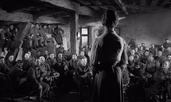 Movie still from “Paths of Glory” (1957), directed by Stanley Kubrick – A woman standing in front of a group of men; Wide shot, Over the shoulder angle