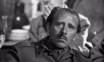 Movie still from “Paths of Glory” (1957), directed by Stanley Kubrick – An old photo of a man in a uniform smoking a cigarette; Close Up shot, Over the shoulder angle