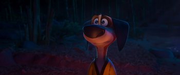 Movie still from “Paws of Fury: The Legend of Hank” (2022), directed by Chris Bailey – A dog with a brown and black coat is standing in the woods; Close Up shot, Over the shoulder angle