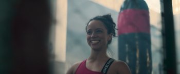 Movie still from “Perfect Addiction” (2023), directed by Castille Landon – A woman smiling for the camera while wearing a red tank top; Close Up shot, Low angle