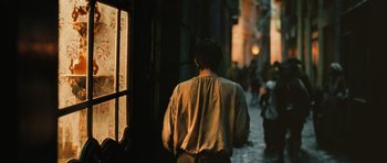 Movie still from “Perfume: The Story of a Murderer” (2006), directed by Tom Tykwer – A man walking down the street in the dark; Medium shot, Over the shoulder angle