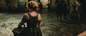 Movie still from “Perfume: The Story of a Murderer” (2006), directed by Tom Tykwer – A woman in a green dress is standing in the street; Medium shot, Over the shoulder angle