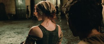 Movie still from “Perfume: The Story of a Murderer” (2006), directed by Tom Tykwer – A woman with red curly hair wearing a hat; Medium shot, Over the shoulder angle