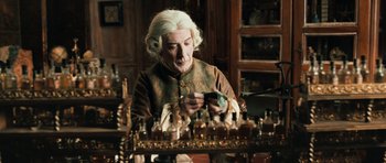 Movie still from “Perfume: The Story of a Murderer” (2006), directed by Tom Tykwer – An old man looking at a cell phone in front of a table full of bottles; Medium shot, High angle