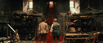 Movie still from “Perfume: The Story of a Murderer” (2006), directed by Tom Tykwer – Two men standing in front of a wall with red roses; Wide shot, High angle