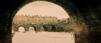 Movie still from “Perfume: The Story of a Murderer” (2006), directed by Tom Tykwer – An arch bridge with a view of a river and buildings; Extreme Wide shot, High angle
