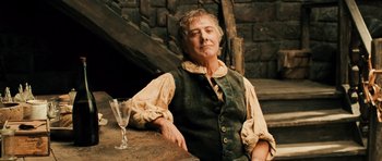 Movie still from “Perfume: The Story of a Murderer” (2006), directed by Tom Tykwer – An older man sitting at a table with a glass of wine; Medium shot, Low angle