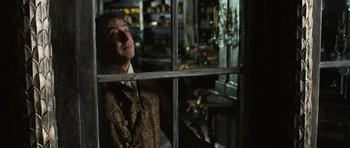 Movie still from “Perfume: The Story of a Murderer” (2006), directed by Tom Tykwer – An old man looking out a window in a store; Medium shot, Over the shoulder angle