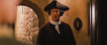 Movie still from “Perfume: The Story of a Murderer” (2006), directed by Tom Tykwer – A man wearing a hat and a brown coat; Close Up shot, Over the shoulder angle