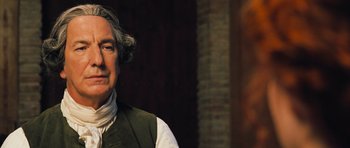 Movie still from “Perfume: The Story of a Murderer” (2006), directed by Tom Tykwer – An older man in a green vest is smiling; Close Up shot, Over the shoulder angle