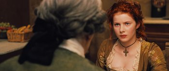 Movie still from “Perfume: The Story of a Murderer” (2006), directed by Tom Tykwer – A red headed woman in a brown and white dress and an old man in a wig; Close Up shot, Over the shoulder angle