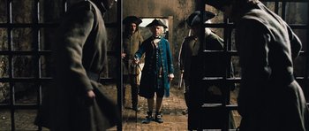 Movie still from “Perfume: The Story of a Murderer” (2006), directed by Tom Tykwer – A group of men standing around in a room; Wide shot, Low angle